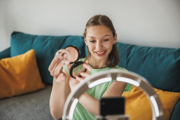 Ein süßes Teenie-Vloggerin überträgt Live-Übertragungen von Make-up-Tutorials für ihre Follower per Smartphone bei ihr zu Hause.