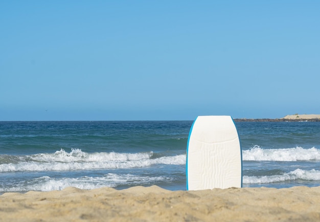 Ein Surfbrett ist am Strand vor dem Meer.
