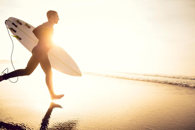 Foto ein surfer mit seinem surfbrett läuft zu den wellen