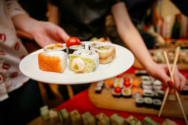 Ein Sushi-Mittagessen, Sushi im Teller, Hände mit Stäbchen