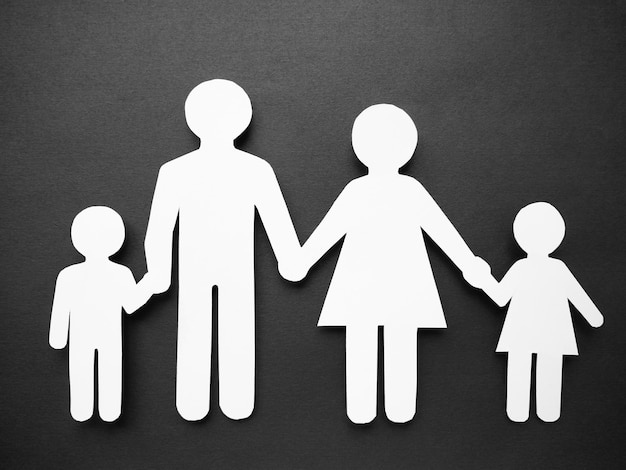 Ein Symbol einer Person und einer Familie aus weißem Papier auf einer schwarzen Oberfläche.