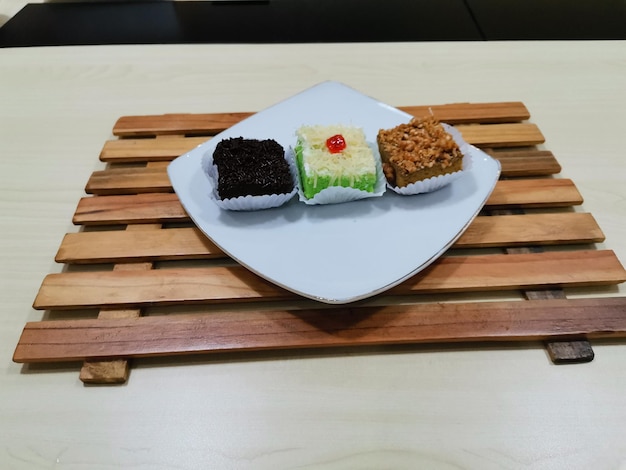 Ein Tablett mit Desserts auf einem Holztablett mit einem roten und grünen Kuchen darauf.