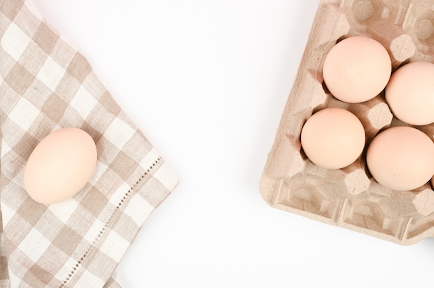 Ein Tablett mit Eiern auf einem weißen Tisch. Öko-Tablett mit Eiern auf weißem Hintergrund, der Trend des Minimalismus, Draufsicht. Eierablage