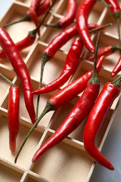 Ein Tablett mit roten Chilischoten mit Holzgriff.