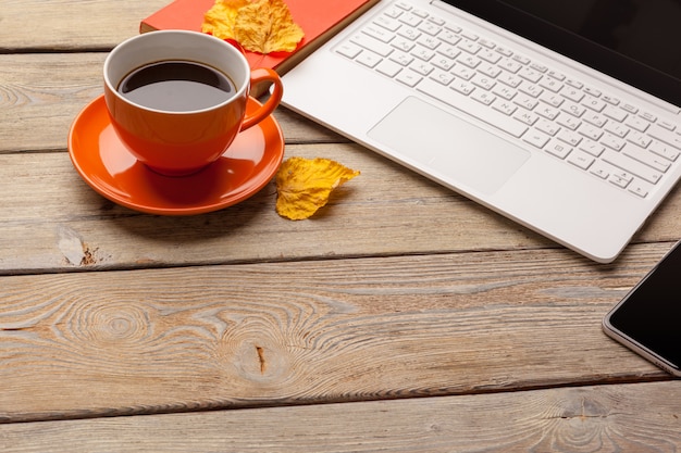 Ein Tasse Kaffee auf der orange Platte auf der Holzoberflächetabelle