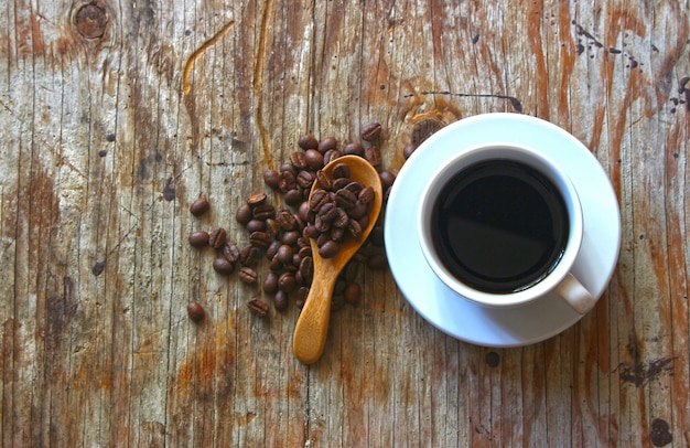 Ein Tasse Kaffee auf Holztisch mit Kaffeebohnen und Holzlöffel