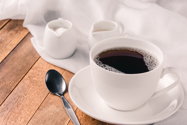 Ein Tasse Kaffee, eine Milch und ein Zucker auf Holztisch