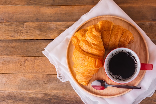 Foto ein tasse kaffee- und hörnchenbrot auf holztisch, draufsicht mit kopienraum