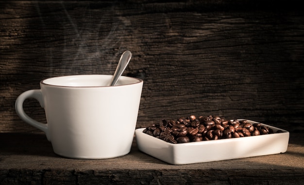 Ein Tasse Kaffee und Kaffeebohnen auf einem alten Holztisch.