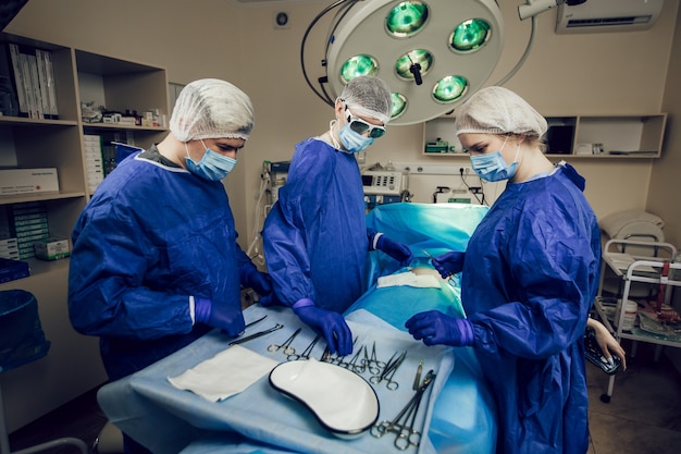 Ein Team von Chirurgen in blauer Uniform operiert einen Patienten in einem Krankenhaus