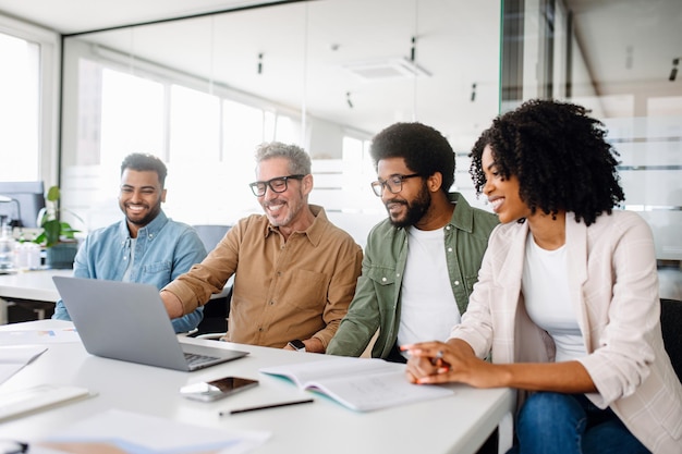 Ein Team von Fachleuten teilt einen fröhlichen Moment um einen Laptop