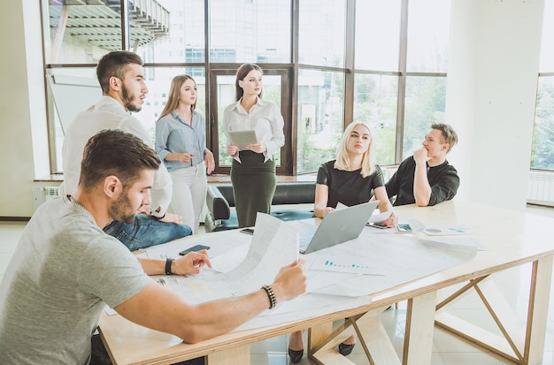 Ein Team von schönen jungen Fachleuten arbeitet an einem Projekt Laptoppapier mit Diagrammen