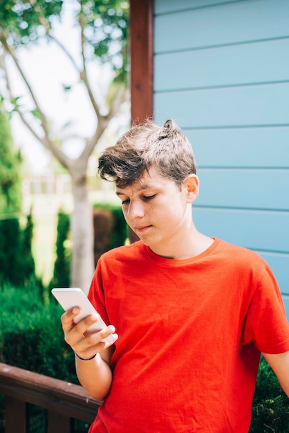 Ein Teenager benutzt im Garten ein Telefon.