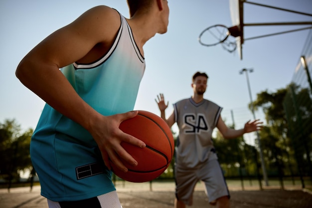 Ein Teenager, der sich darauf vorbereitet, den Ball in den Korb zu werfen. Glücklicher Vater und Sohn spielen Basketball auf einem Straßenplatz im Freien