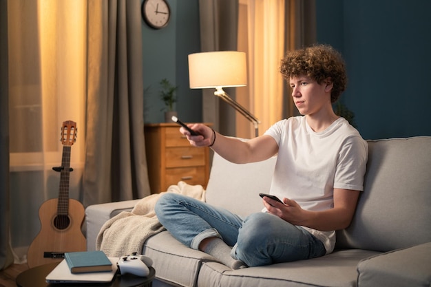 Ein Teenager, eine Brünette mit lockigem Haar, entspannt sich abends auf der Couch im Wohnzimmer