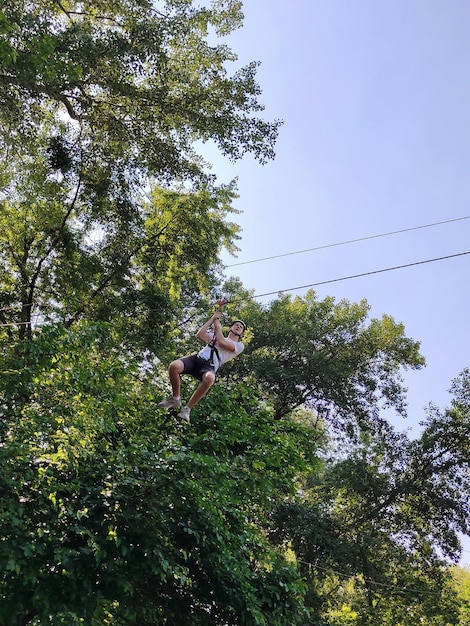 Ein Teenager fährt in einem Seilvergnügungspark mit einer Seilbahn das Seil hinunter