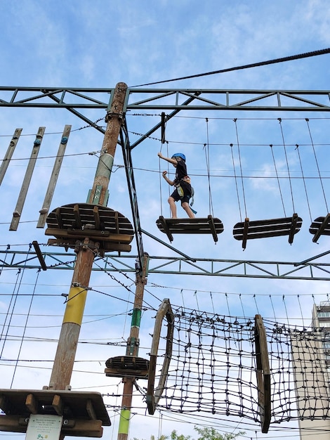 Ein Teenager geht auf einer Seil-Hängebrücke in einem Seil-Vergnügungspark. Blick von unten