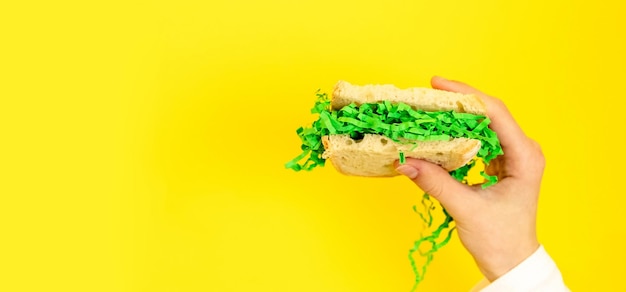 Ein Teenager hält ein Brot-Sandwich mit Ostergrünem Heu