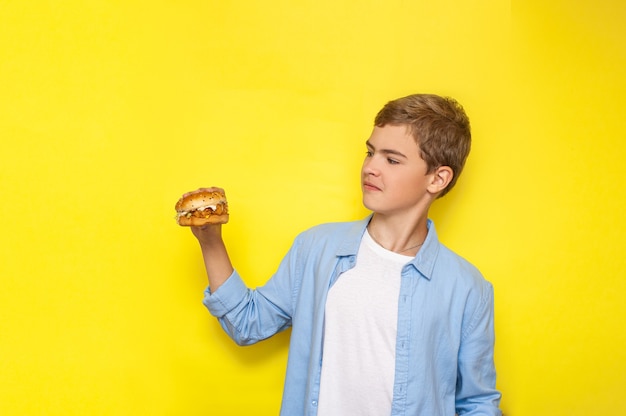 Ein Teenager hält einen Burger in der Hand a