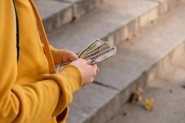 Ein Teenager in einem orangefarbenen Hoodie zählt Taschengeld