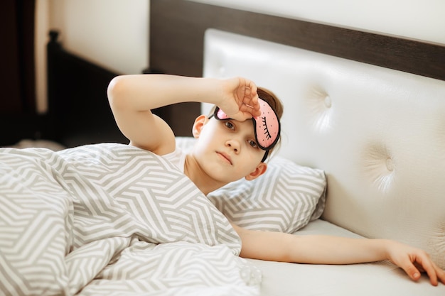 Foto ein teenager in einer nachtmaske liegt auf dem bett und wacht morgens auf