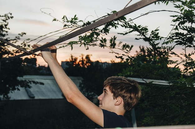 Ein Teenager kümmert sich um einen jungen Baum durch Gartenarbeit, um
