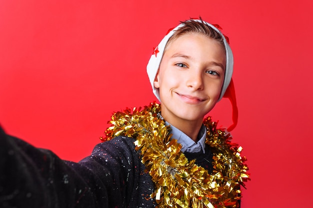 Ein Teenager macht ein Selfie in einer Weihnachtsmütze und Lametta am Hals