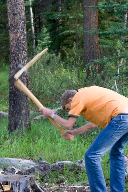 Foto ein teenager schneidet holz mit einer axt im wald