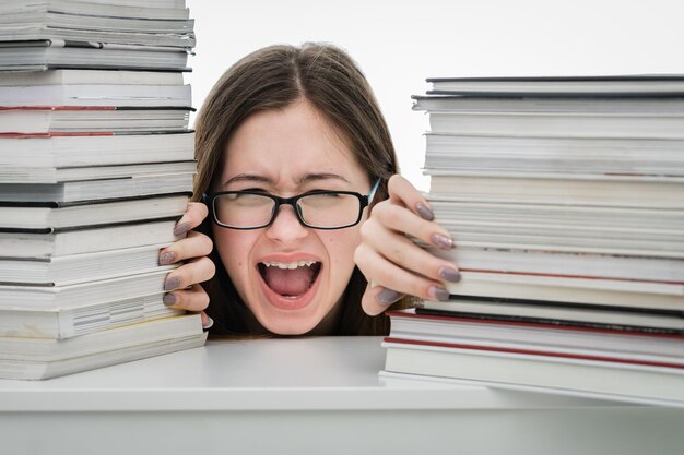 Foto ein teenager schreit vor büchern auf dem tisch gegen einen weißen hintergrund