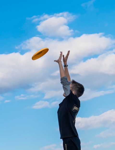 Ein Teenager springt gegen den Himmel und fängt einen Teller Frisbee