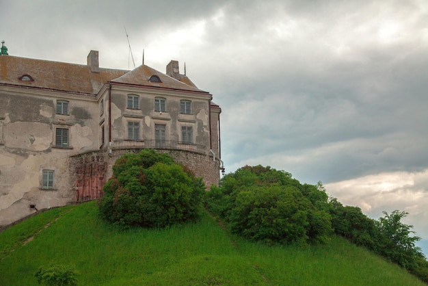 Ein Teil der alten Burg steht bei bewölktem Wetter auf einem grünen Hügel