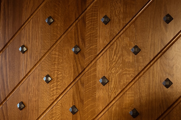 Ein Teil der dekorativen Holzoberfläche verziert mit schwarzen Metallnieten und diagonalen Linien, die von geschossen wurden