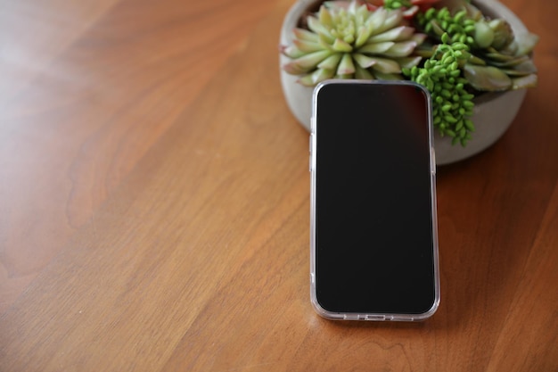 Ein Telefon auf einem Holztisch mit einer Pflanze darauf