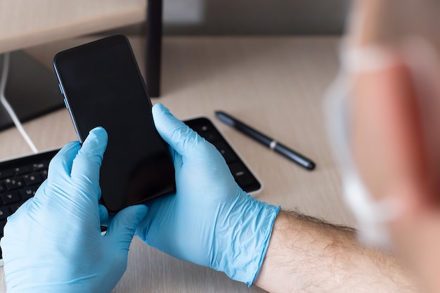 Ein Telefon in der Hand, in Schutzhandschuhen