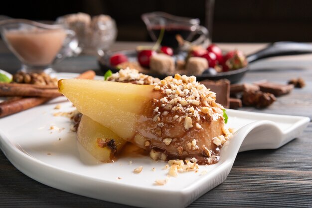 Ein Teller Birnendessert mit Weinsauce auf einem dunklen Holztisch