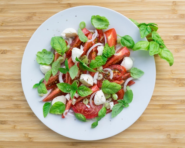 Ein Teller Caprese-Salat auf einem Holztisch