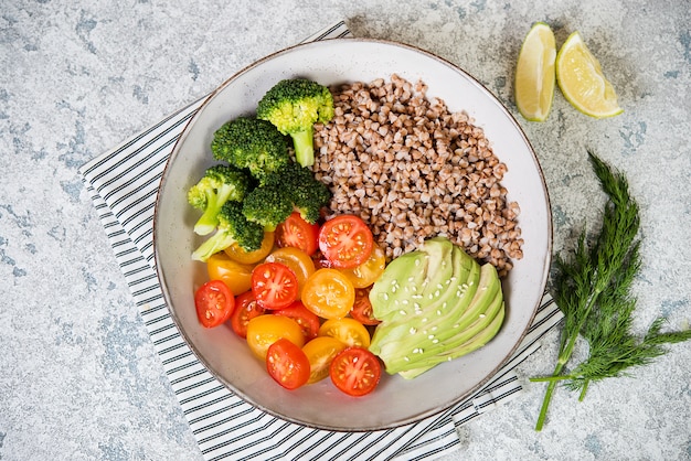 Ein Teller des gesunden veganen Salats zum Mittagessen auf einem grauen Hintergrund.