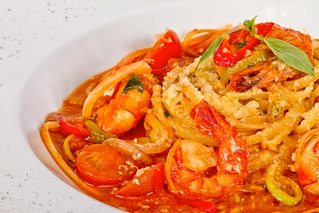 Ein Teller Linguini mit sautierten Garnelen, Tomaten, Chili und Olivenöl