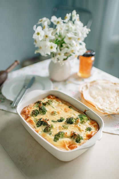 Ein Teller mit Brokkoli und Tortilla auf einem Tisch mit einer Blumenvase.