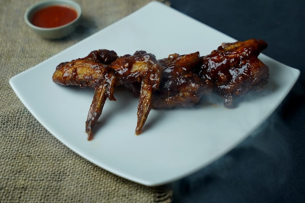 Ein Teller mit Chicken Wings mit Soße darauf