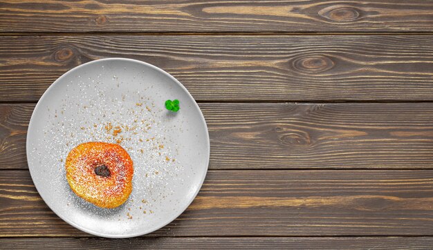 Ein Teller mit einem hausgemachten Donut mit Rohrzucker und Puderzucker, dekoriert mit einem Blatt Minze