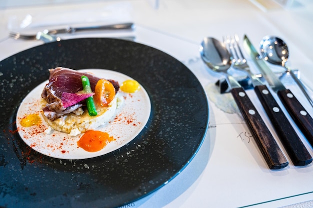 Ein Teller mit Essen, darauf ein Stück Fleisch und auf der rechten Seite ein Messer.