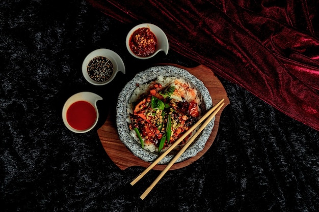 Ein Teller mit Essen mit Stäbchen und einer Schüssel Kimchi.
