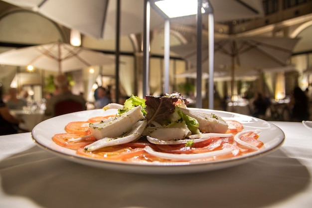 Ein Teller mit geschnittenen Tomaten, garniert mit Salat, Zwiebeln und verschiedenen Käsesorten. Haute-Cuisine-Konzept.