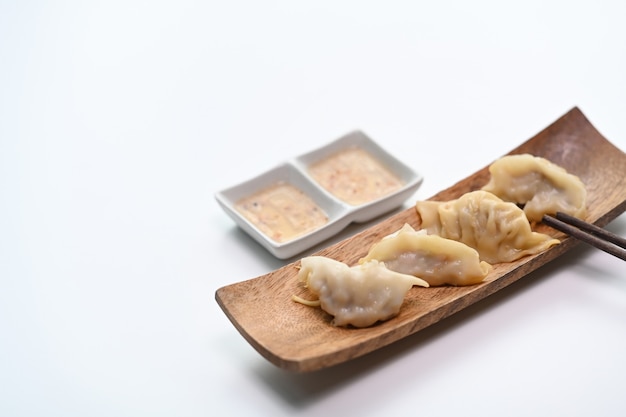 Ein Teller mit japanischen Gyoza-Knödeln auf einem weißen Tisch.