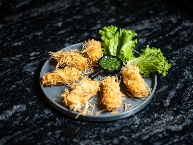 Ein Teller mit knusprig frittierten Paneer-Brötchen mit grüner Soße darauf