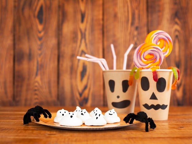 Foto ein teller mit kuchen und gläser mit lutschern nahaufnahme auf einem holztisch. halloween-konzept