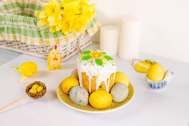 Foto ein teller mit ostereiern und ein kuchen mit gelben blumen darauf.