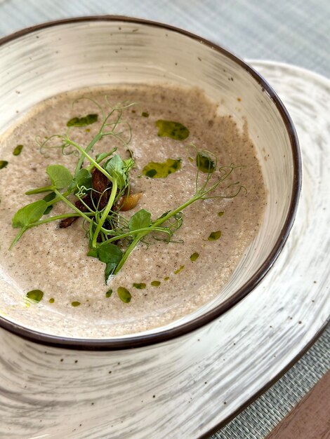 Ein Teller mit Pilzcremesuppe, dekoriert mit Mikrogrüns in der Nähe