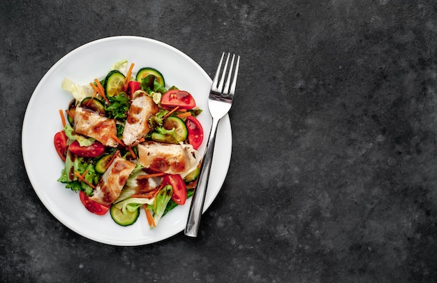 ein Teller mit Salat aus Tomaten, Hühnchen, Gurken, Karotten, Sojasauce in einem Teller